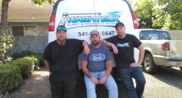 Three men posing in front of a Washbeck service van with company contact information displayed